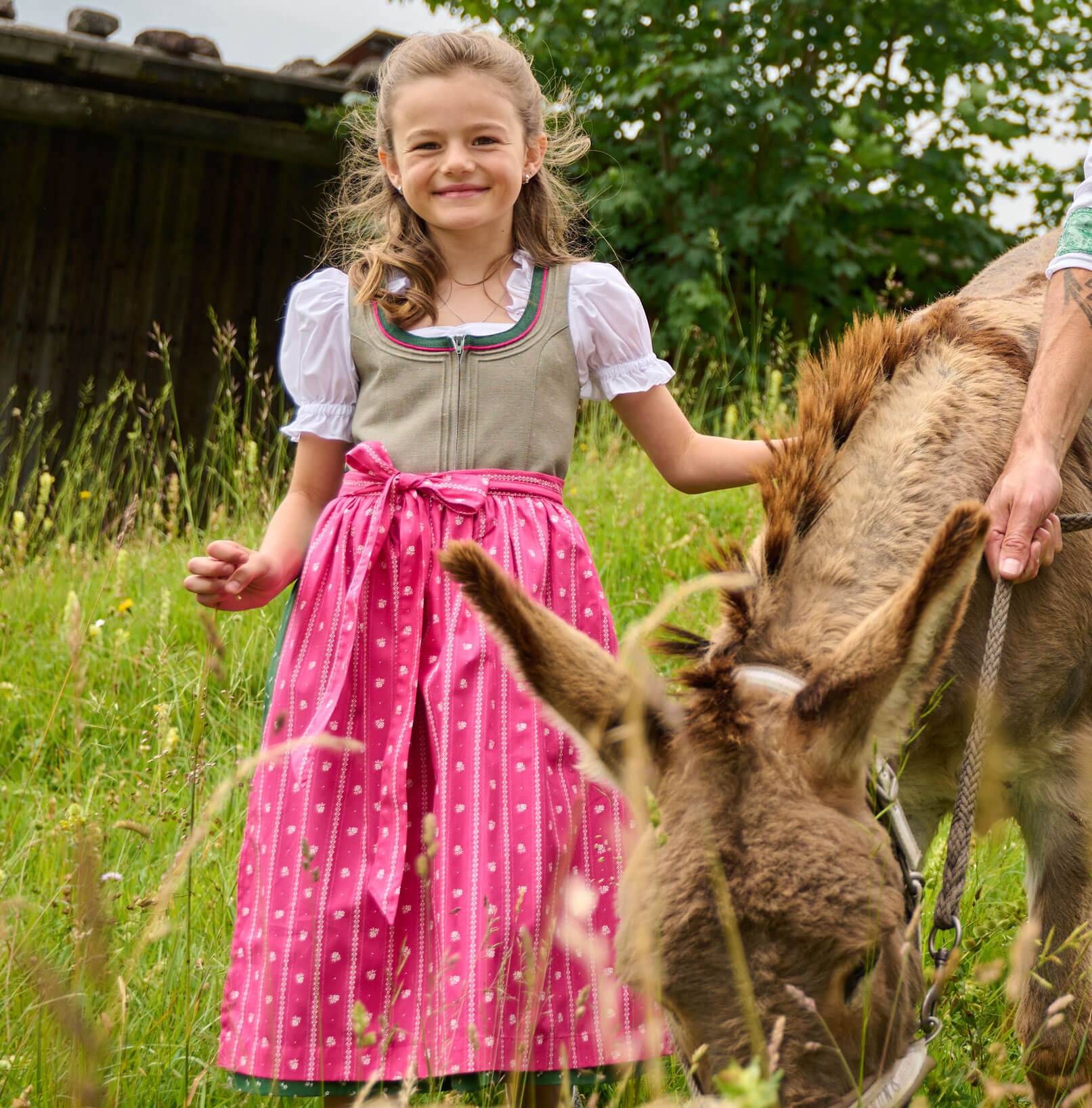 Vorderansicht des Kinder Dirndls "Irmi" in Helloliv-Pink, getragen von einem Model