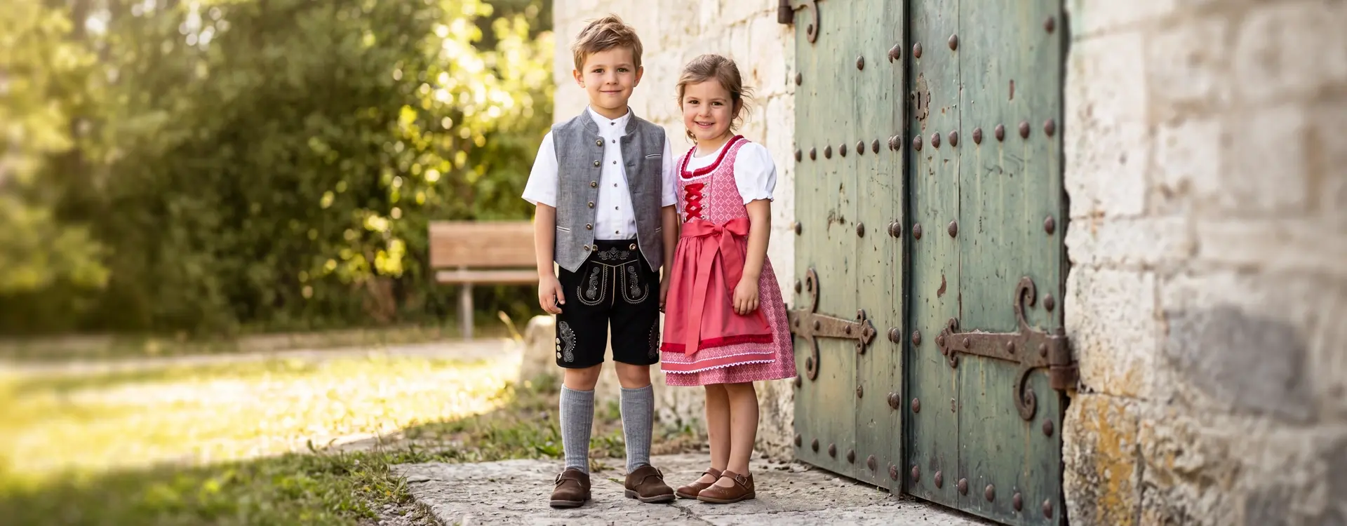 Junge mit Lederhose und Mädchen mit Dirnd vor einem Gebäude