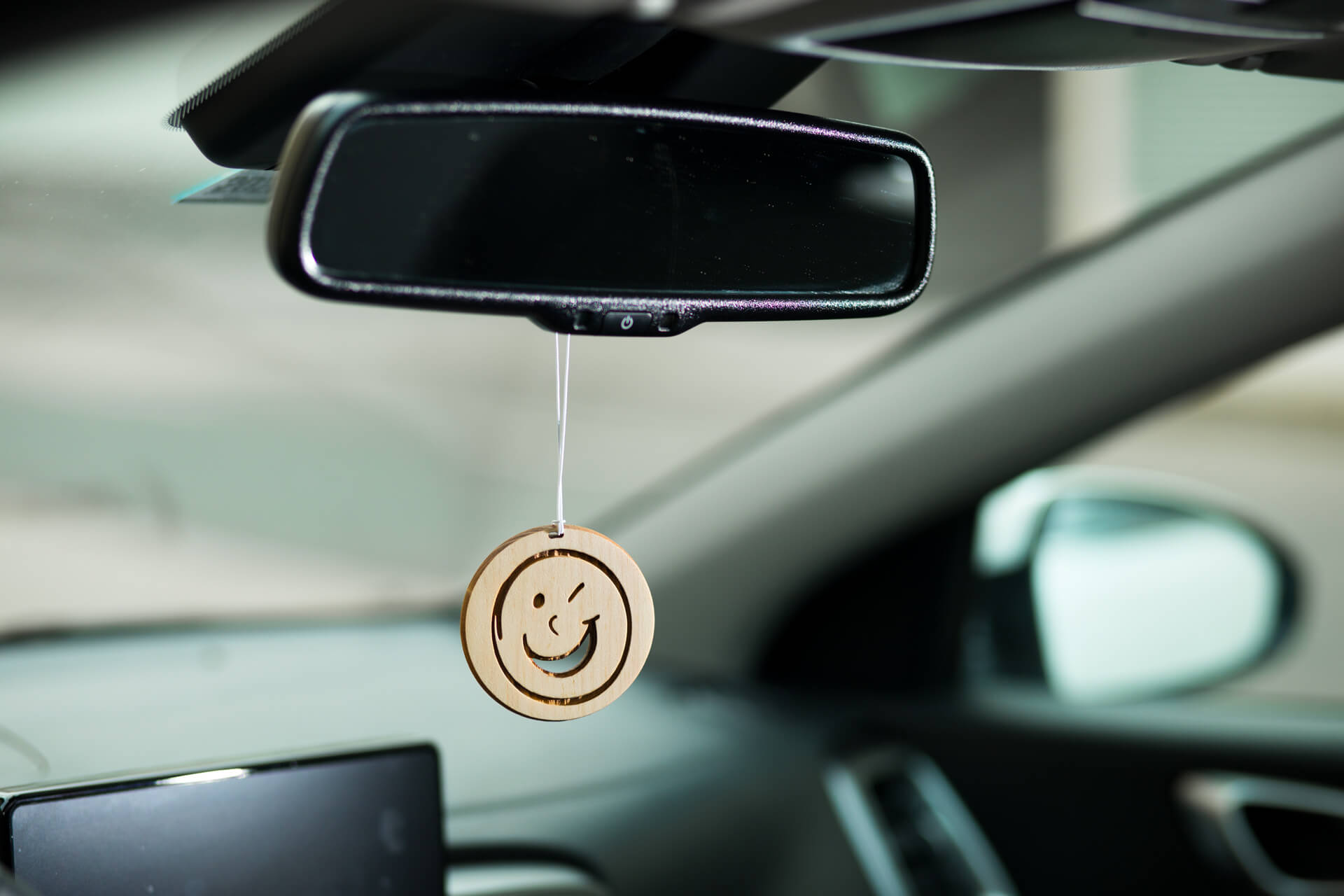 Autoduft aus Zirbe "Smiley", Ansicht hängend im Auto